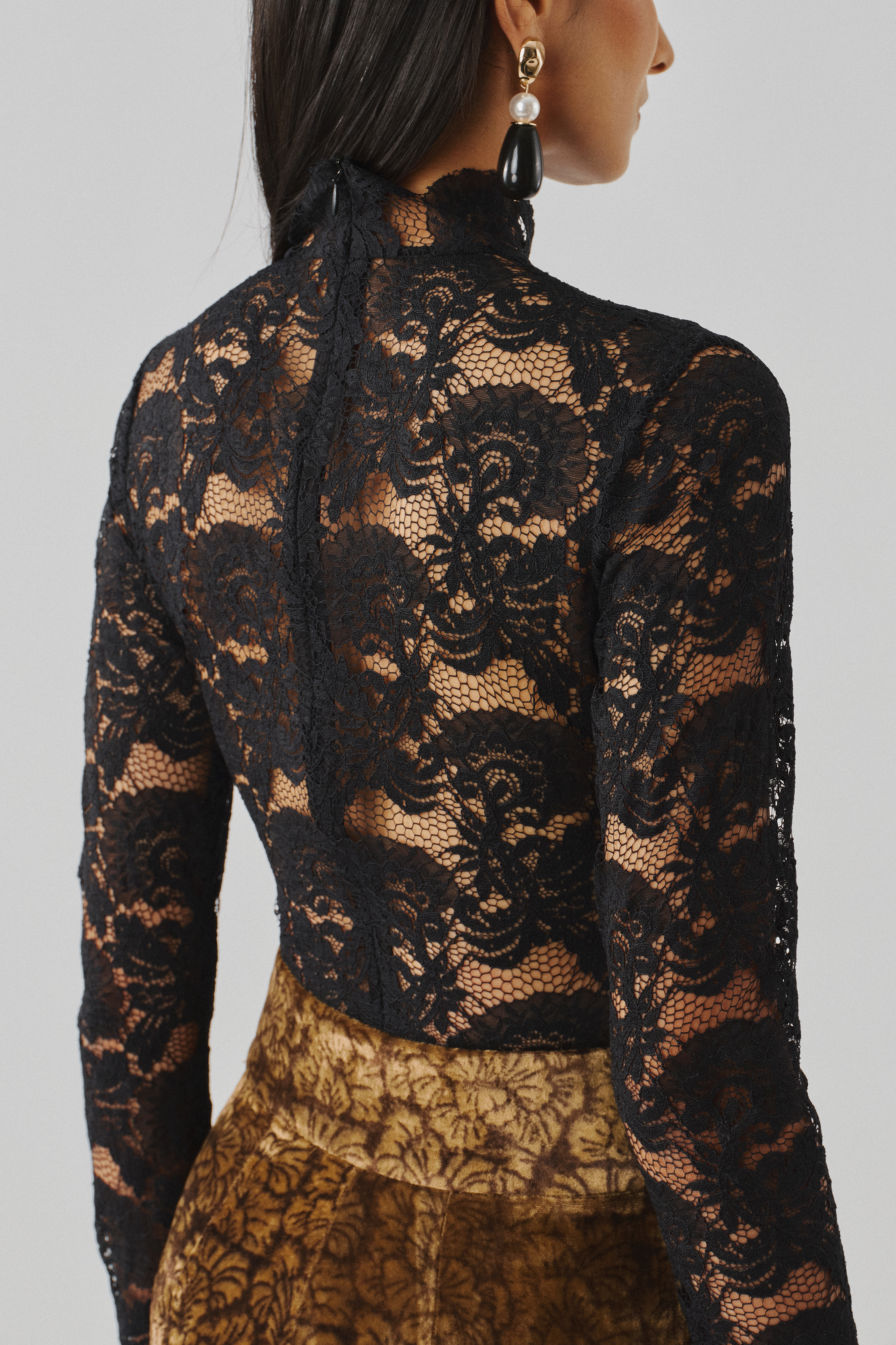 Black lace top with a draped gold skirt, rear profile view