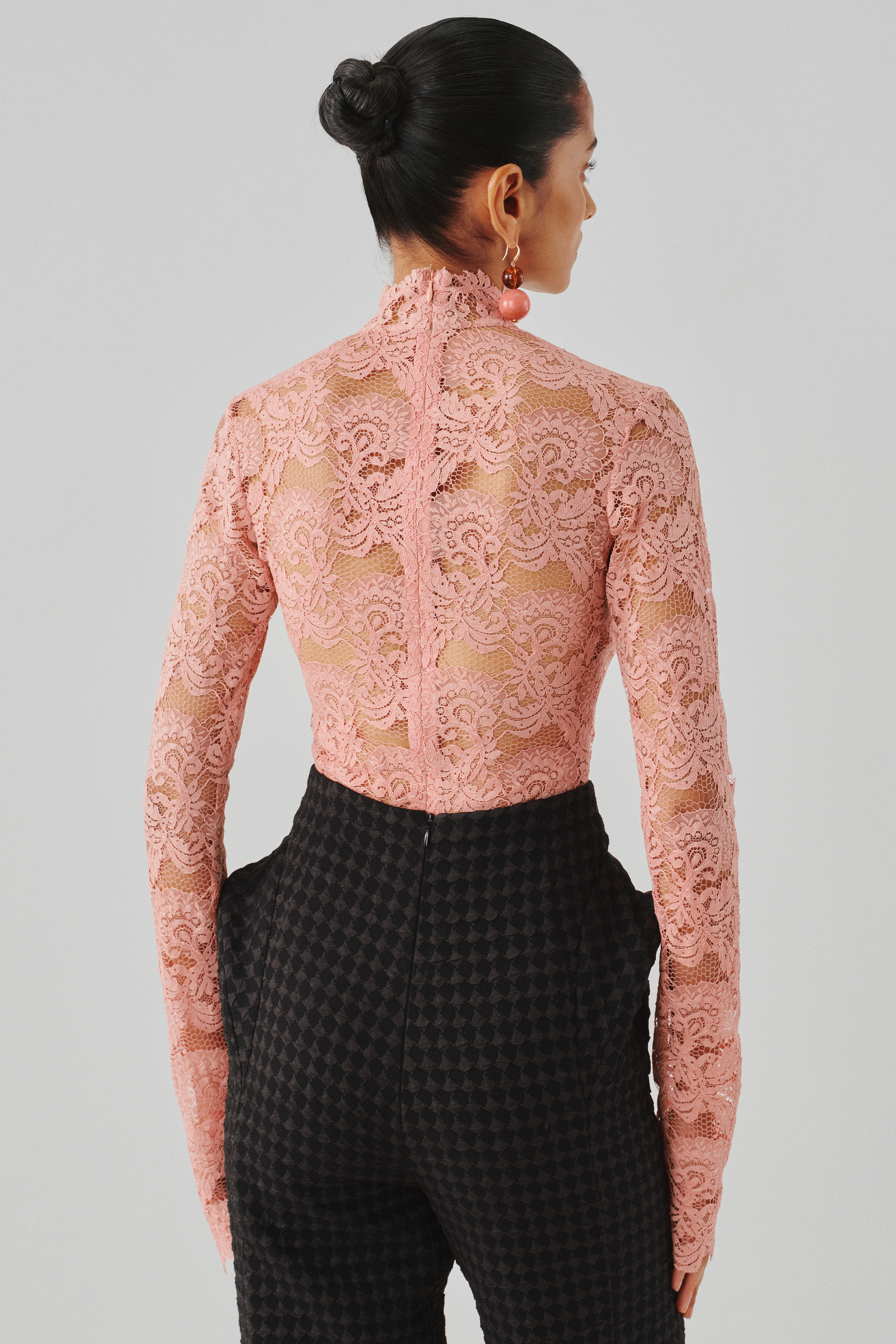 Blush pink lace long-sleeve top with black trousers, rear view