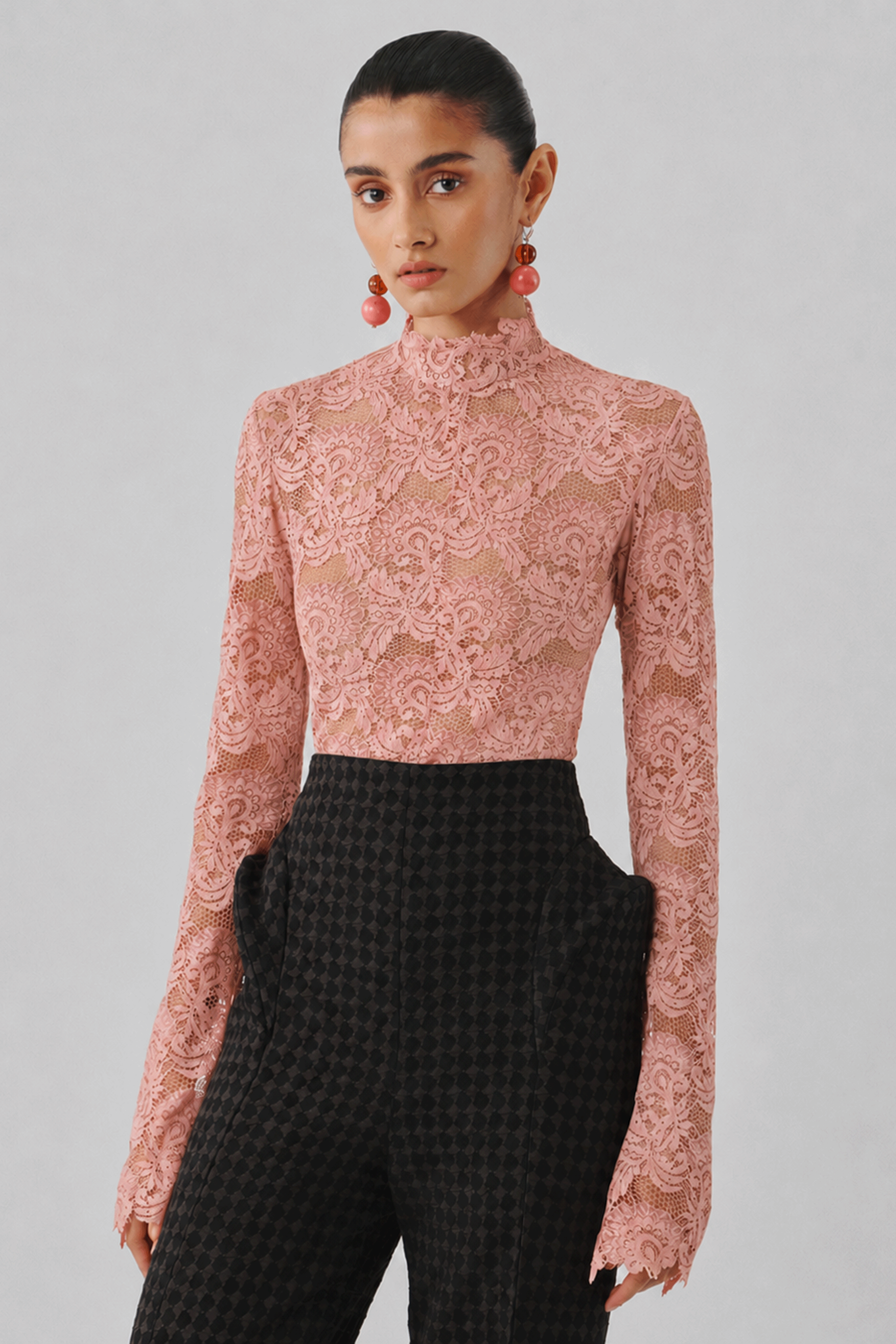 Blush pink lace top with black tailored trousers, close-up view