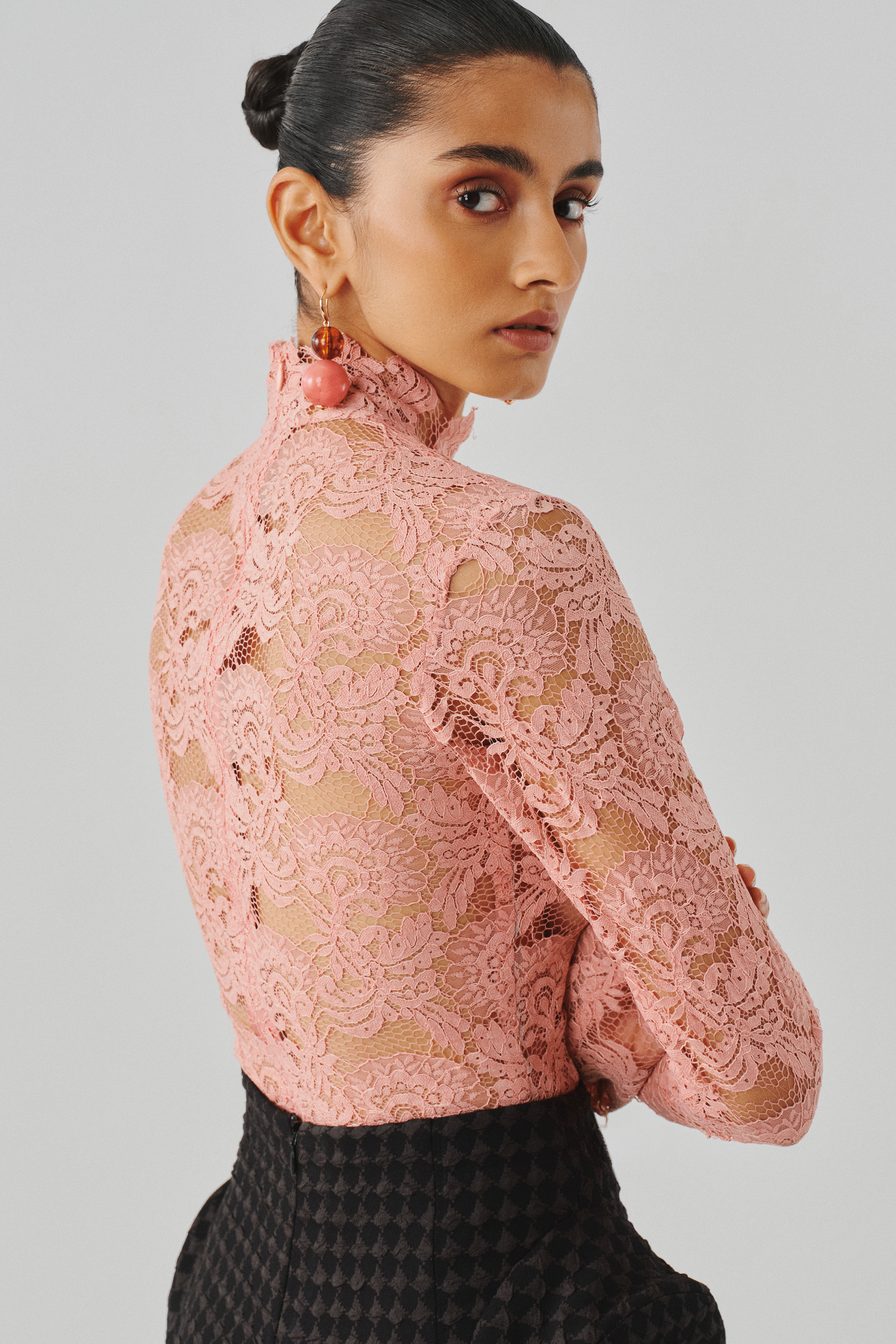 Blush pink lace top with a fitted bodice, rear close-up view