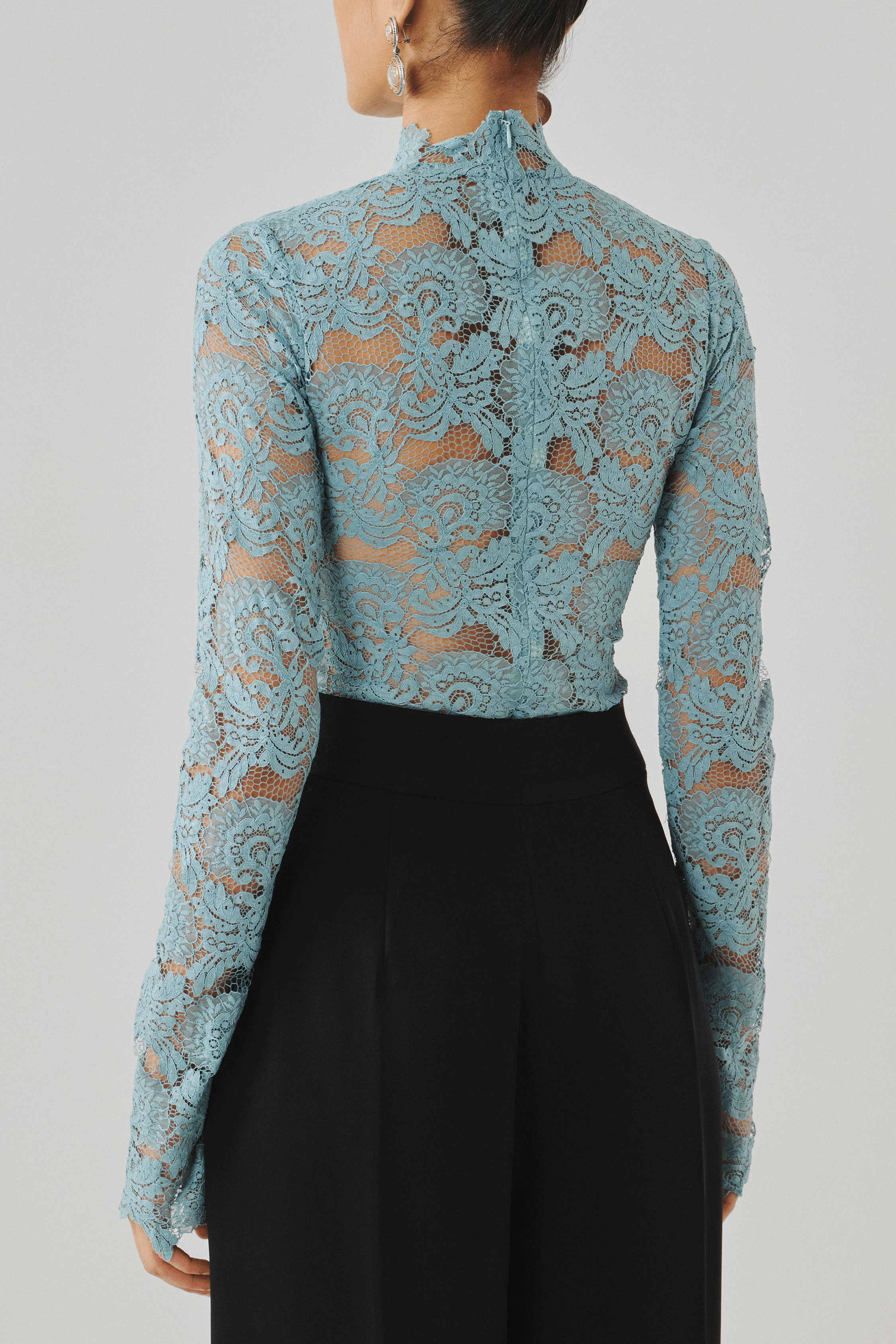 Sky blue lace top styled with black trousers, close-up front view