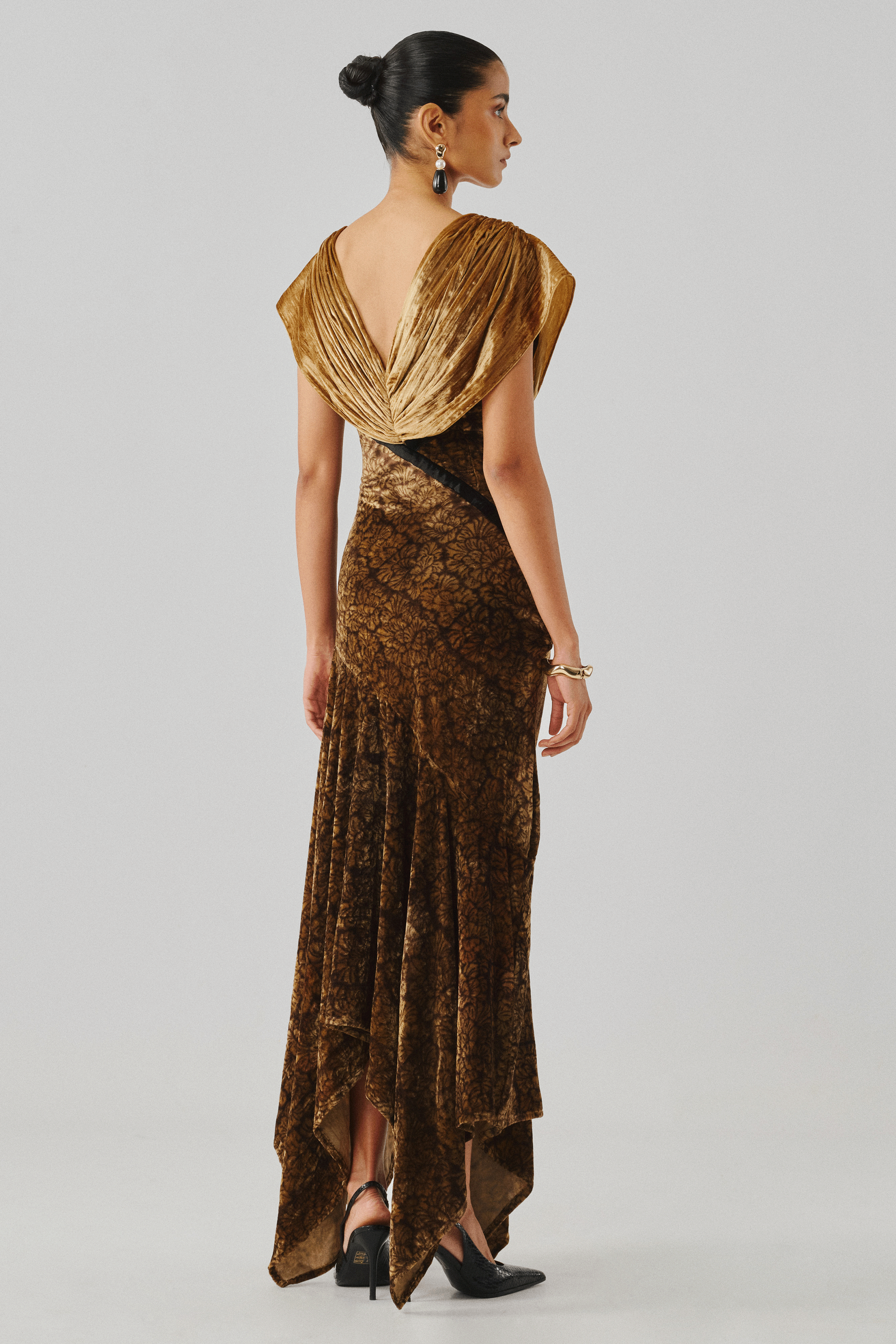 Gold draped gown with an open back detail, rear profile view