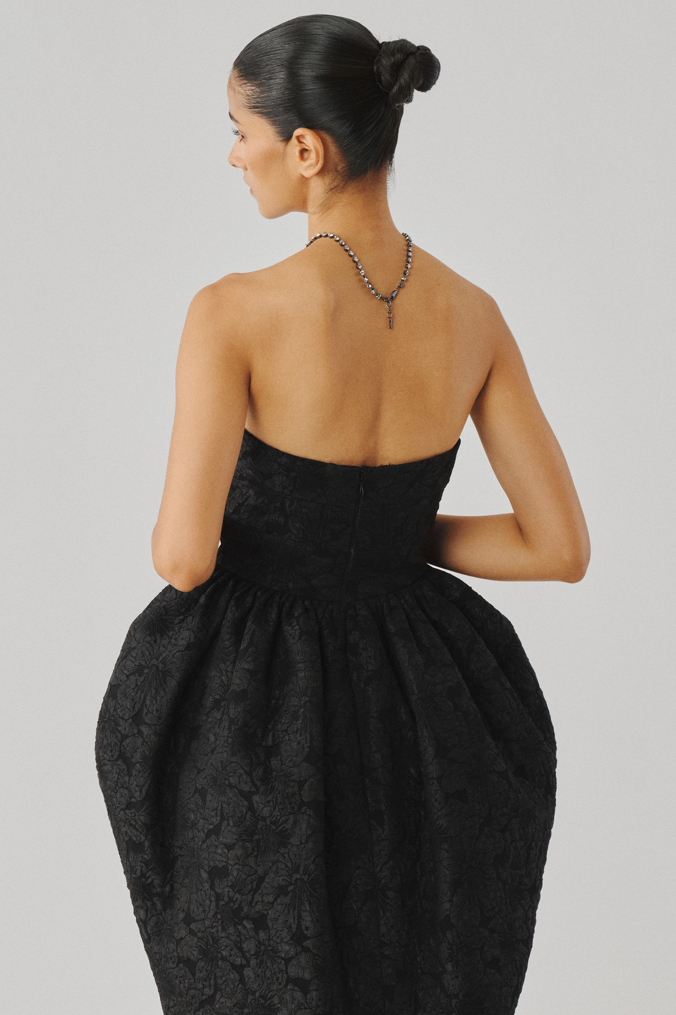 Black strapless gown with a voluminous puffed skirt, side profile