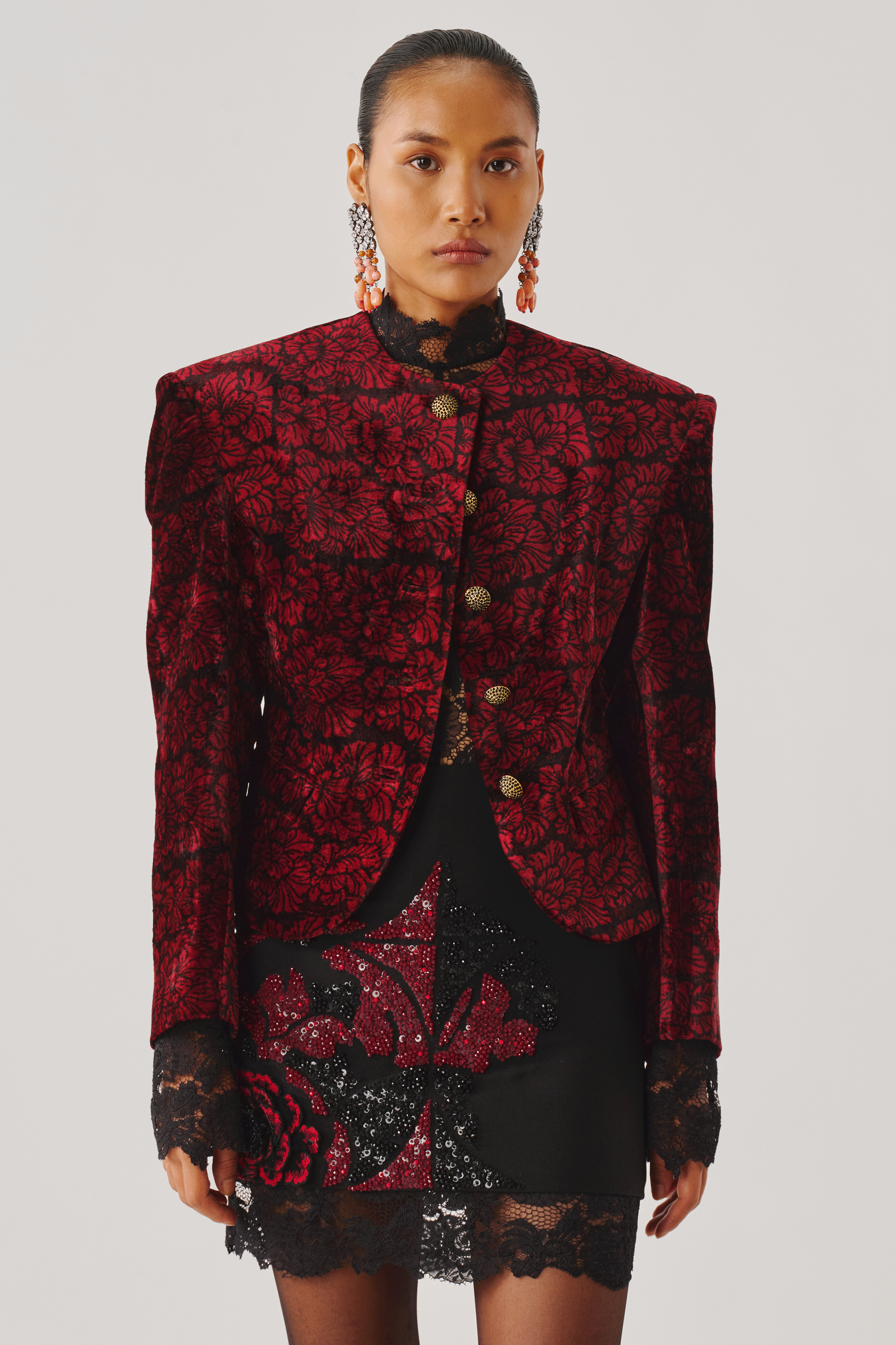 Close-up of a burgundy jacquard jacket over a black lace mini skirt