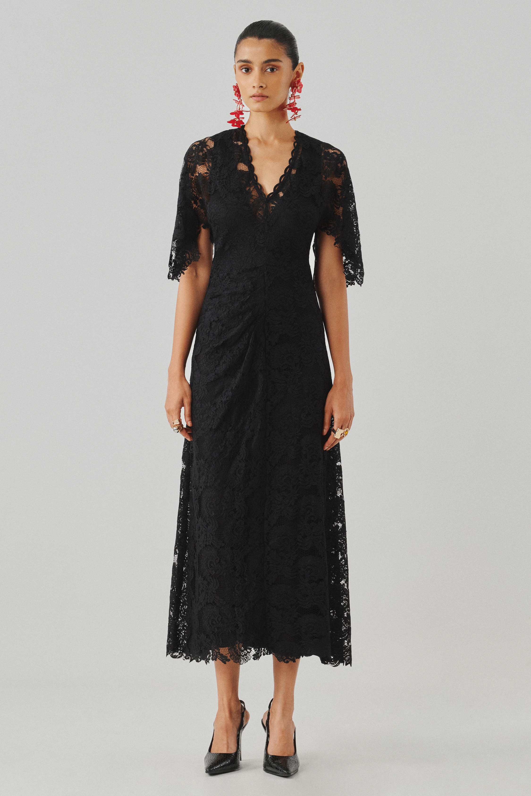 Black lace cape-sleeve top with a draped skirt, side profile view