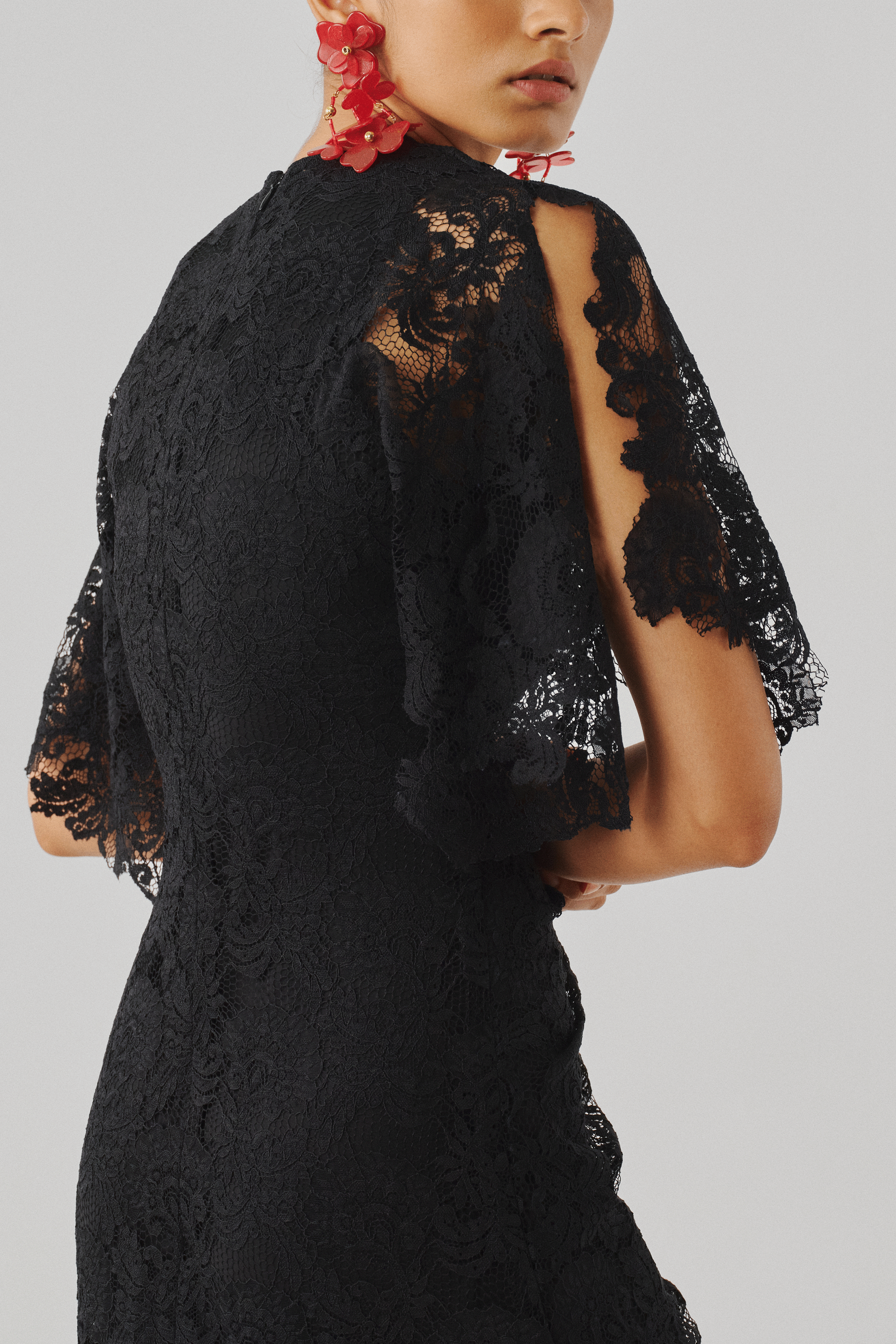 Black lace cape-sleeve top with intricate detailing, close-up rear