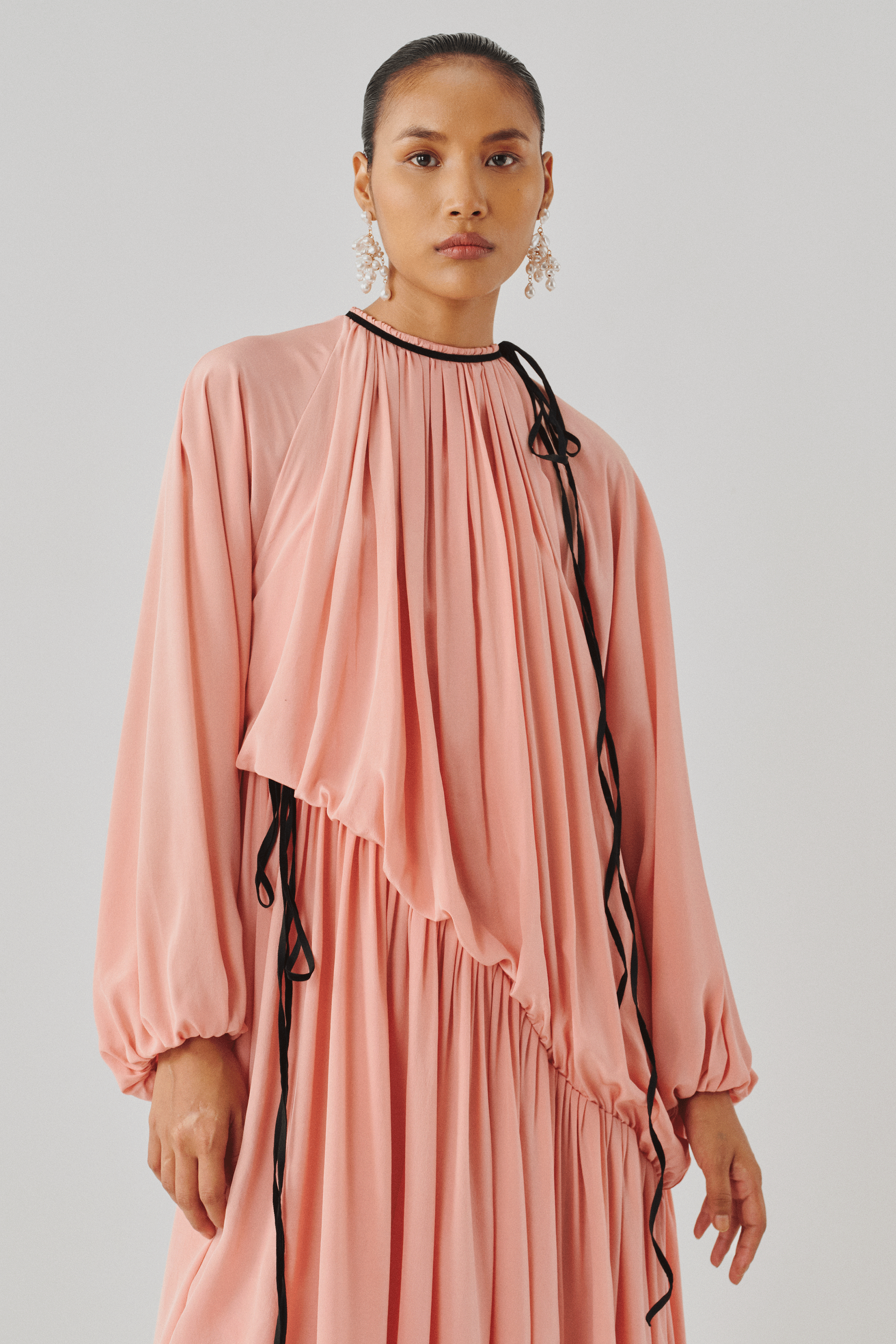 Blush pink tiered dress with ruffled sleeves, side profile view