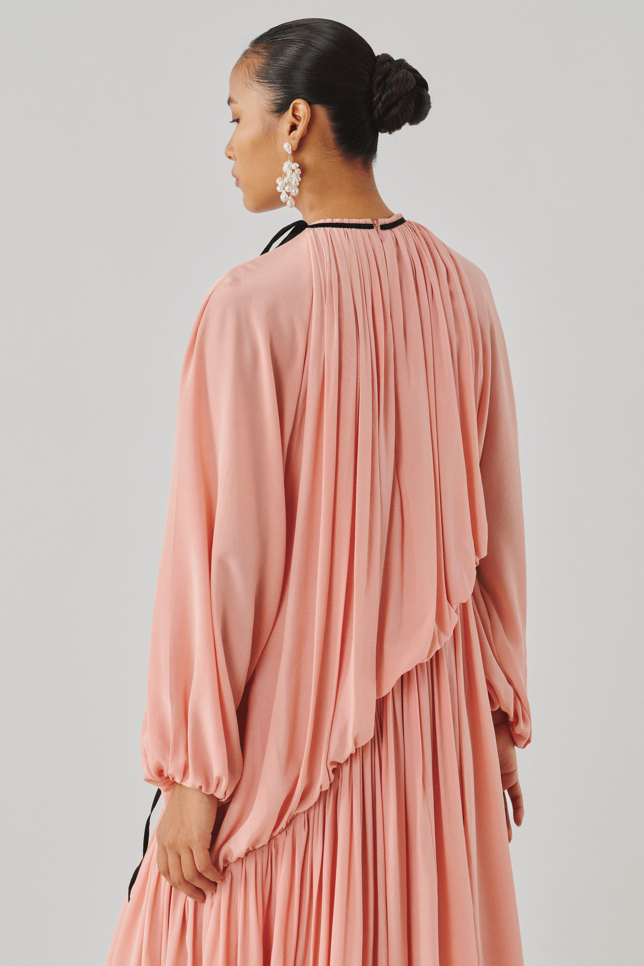 Blush pink draped dress with flowing sleeves, rear profile view