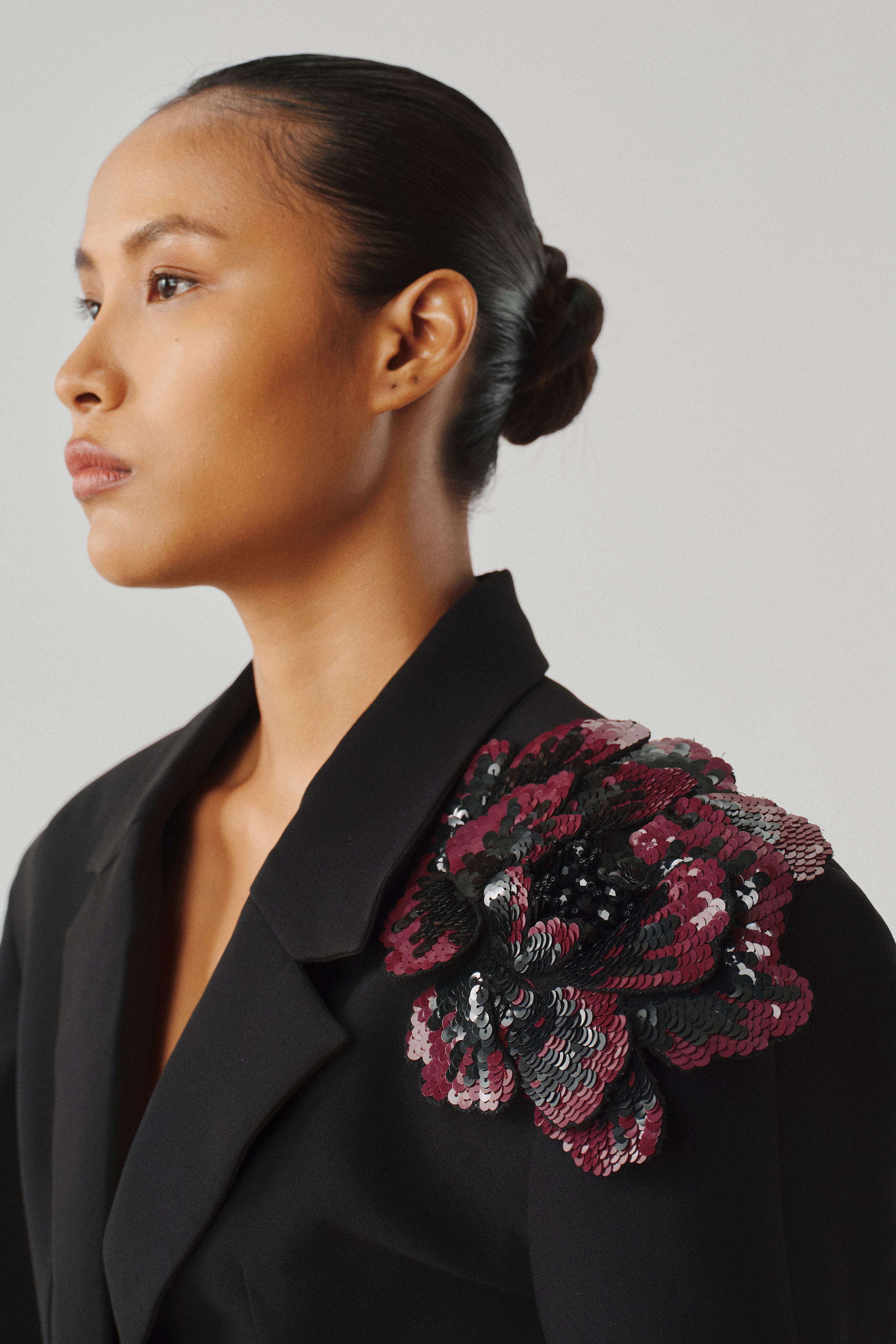 Black tailored blazer with a floral brooch, front close-up view