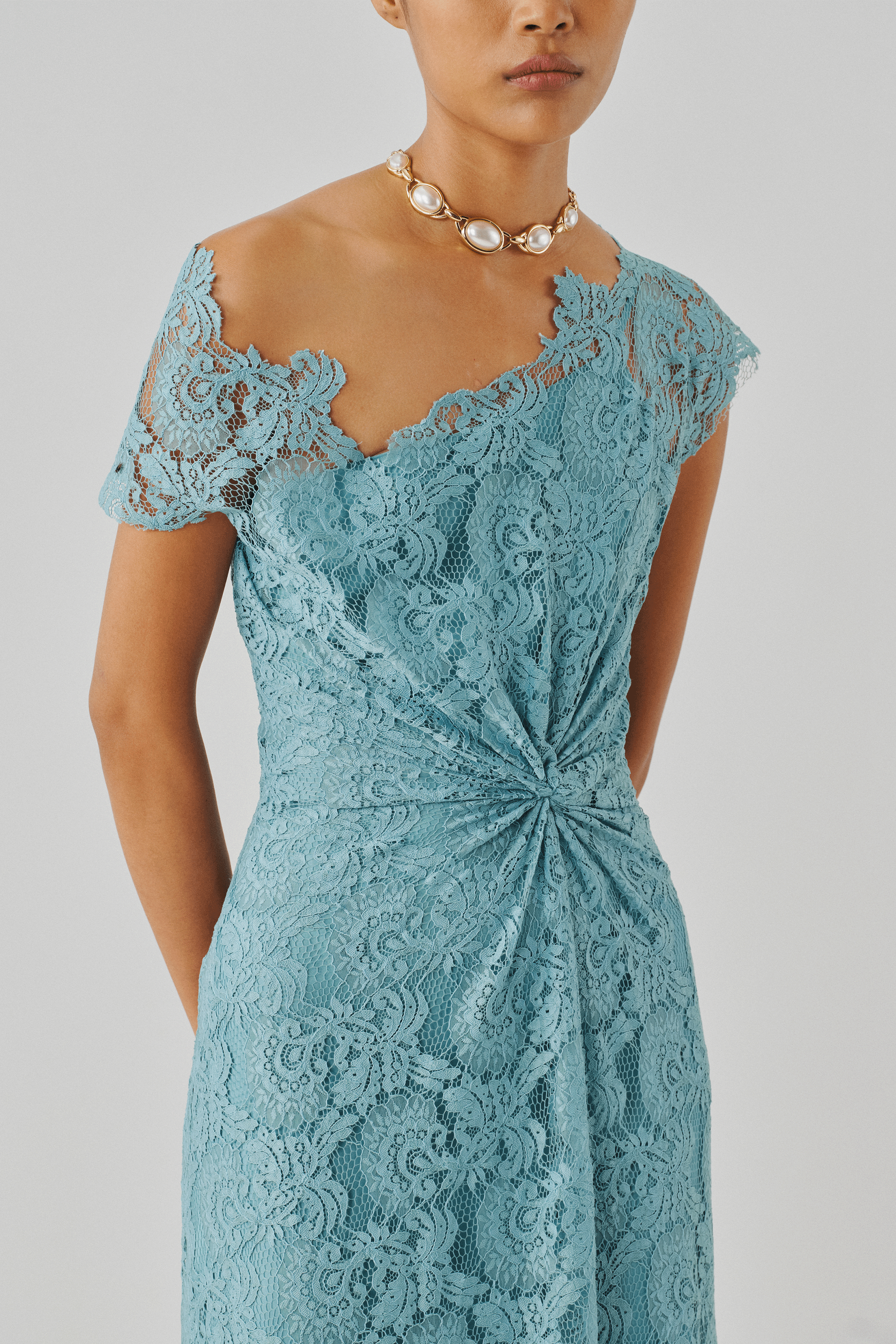 Blush pink lace dress with a draped knot detail, front close-up