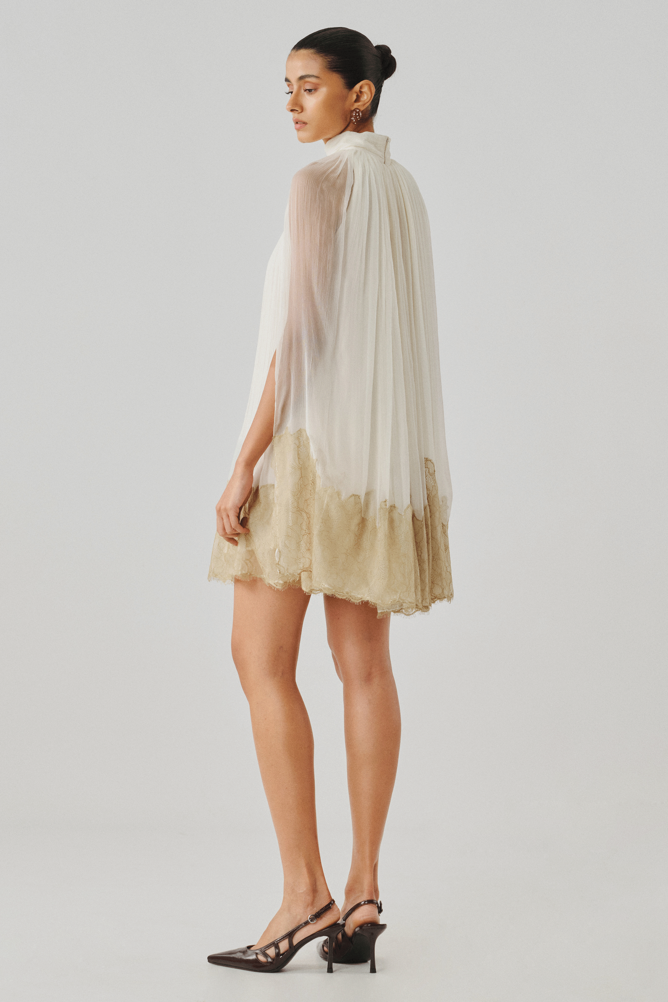Ivory tiered mini dress with a dip-dyed gold hem, side profile view