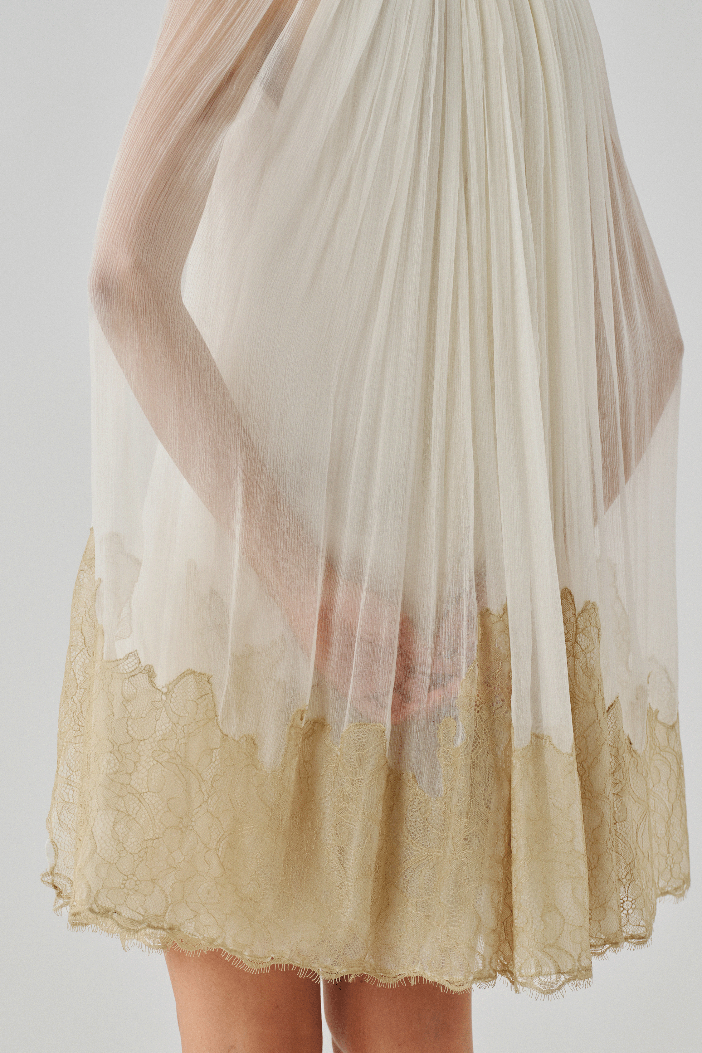 Close-up detail of an ivory gown's gold dip-dyed fringe hemline