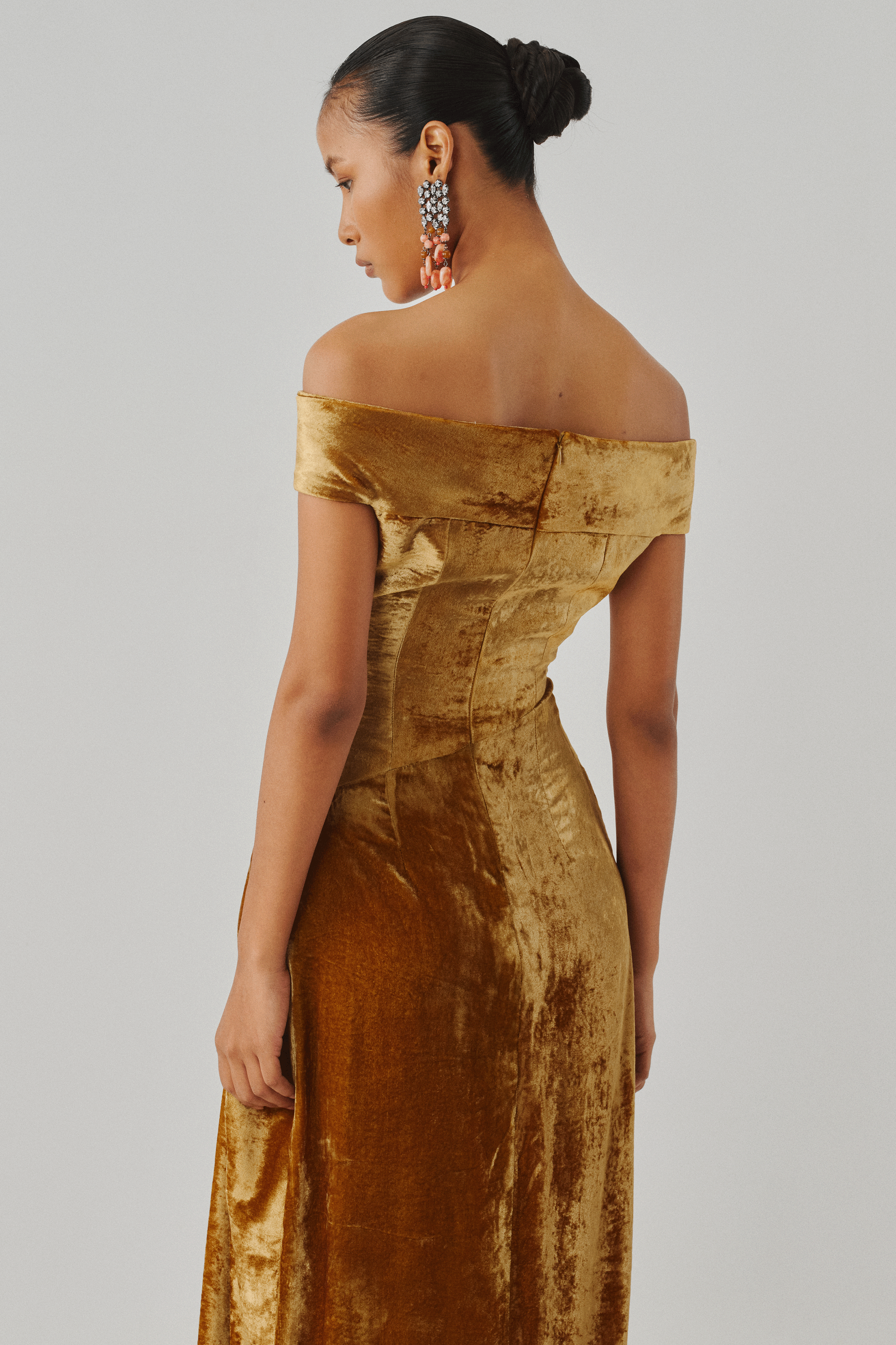 Gold velvet draped gown with an off-shoulder neckline, rear view